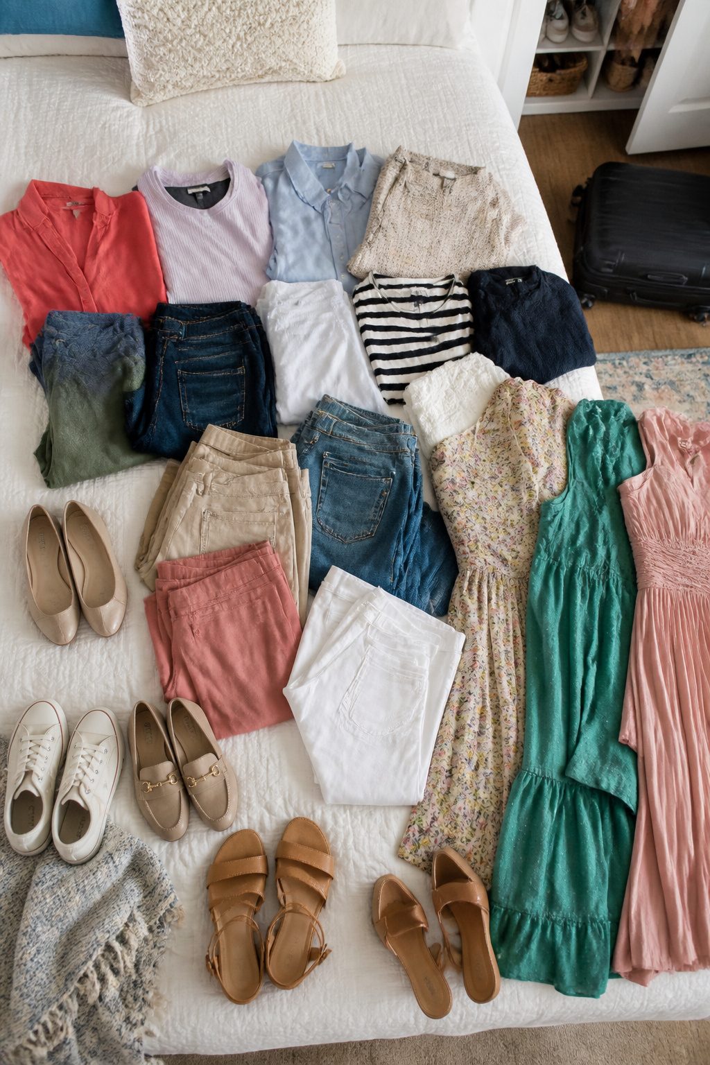 Clothes laid out on a bed by category, including shoes and accessories.